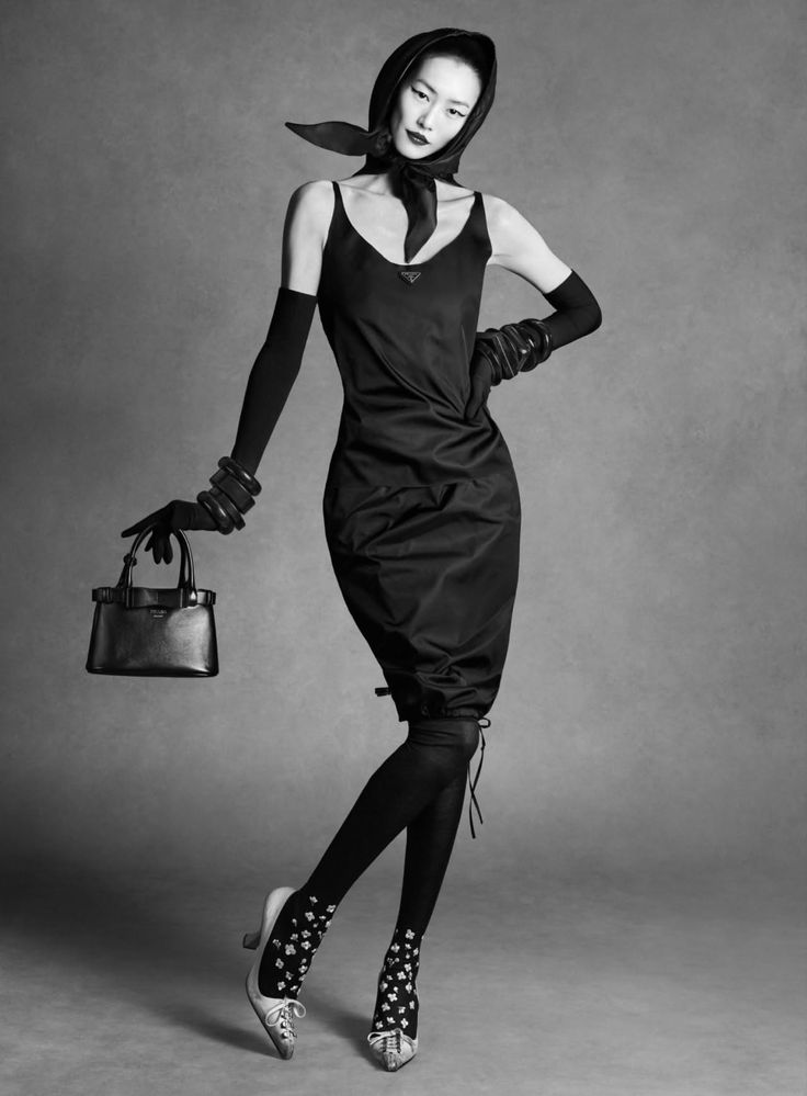 Woman in a black dress, head scarf, and long gloves holding a handbag
