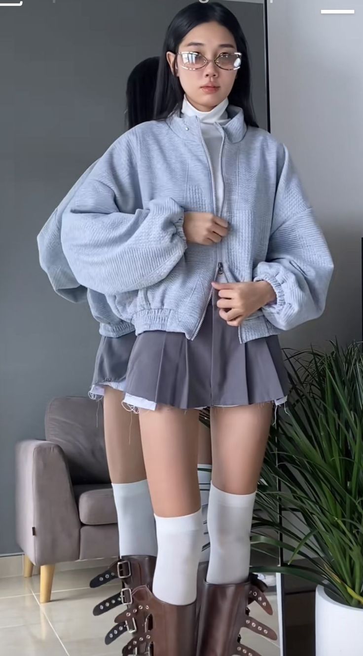 Woman in an oversized jacket and pleated skirt with a mirror reflection