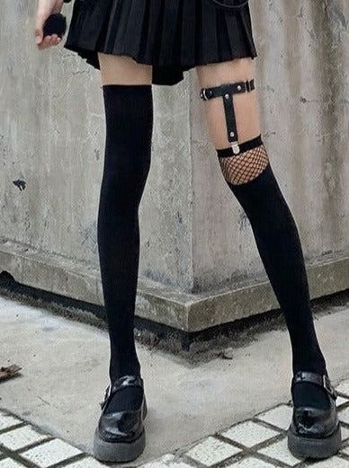 Person wearing a pleated skirt, thigh-high socks, and garter belt outdoors