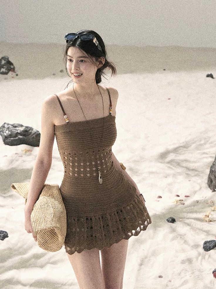 Woman in a brown crochet dress and sunglasses on a sandy beach
