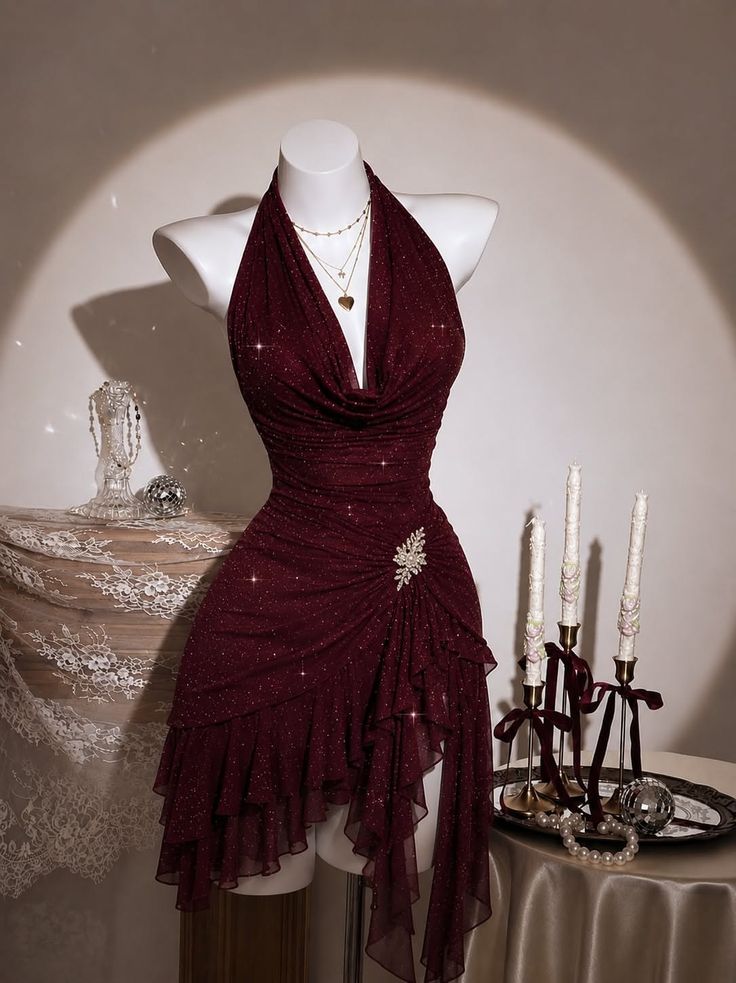 Maroon sparkling halter dress on a mannequin with jewelry and candles