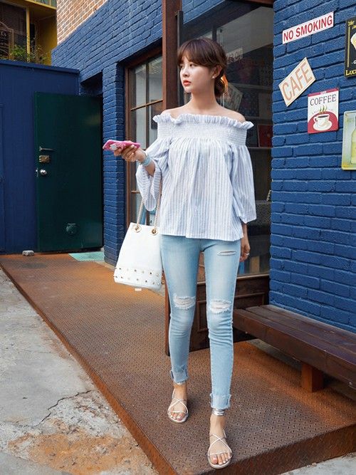 Woman in an off-shoulder top and ripped jeans walking outdoors