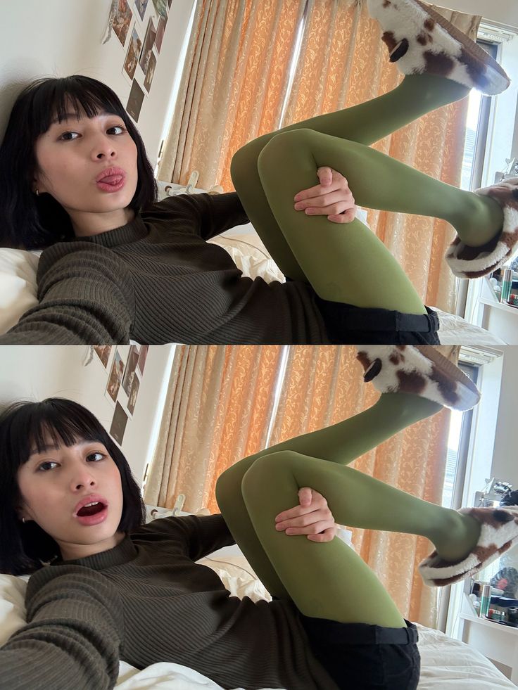 Woman in green tights and cow print slippers lying down with a playful expression