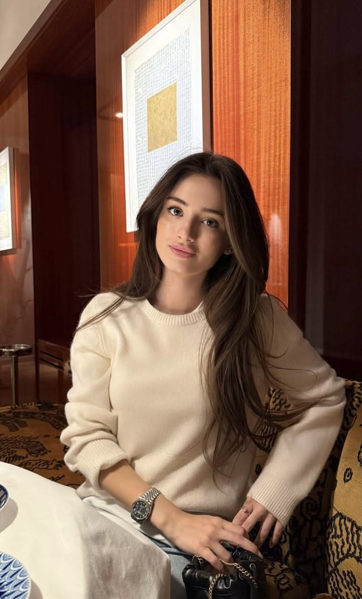 Woman with long brown hair wearing a cream sweater indoors