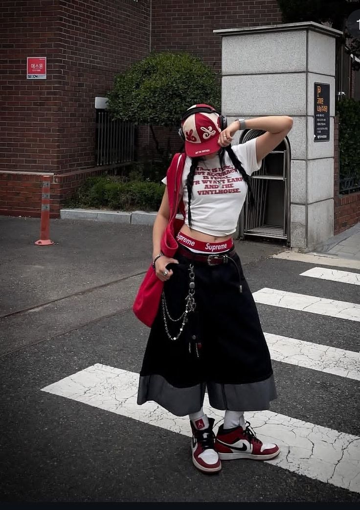 Woman in a crop top, long skirt, and baseball cap on a crosswalk
