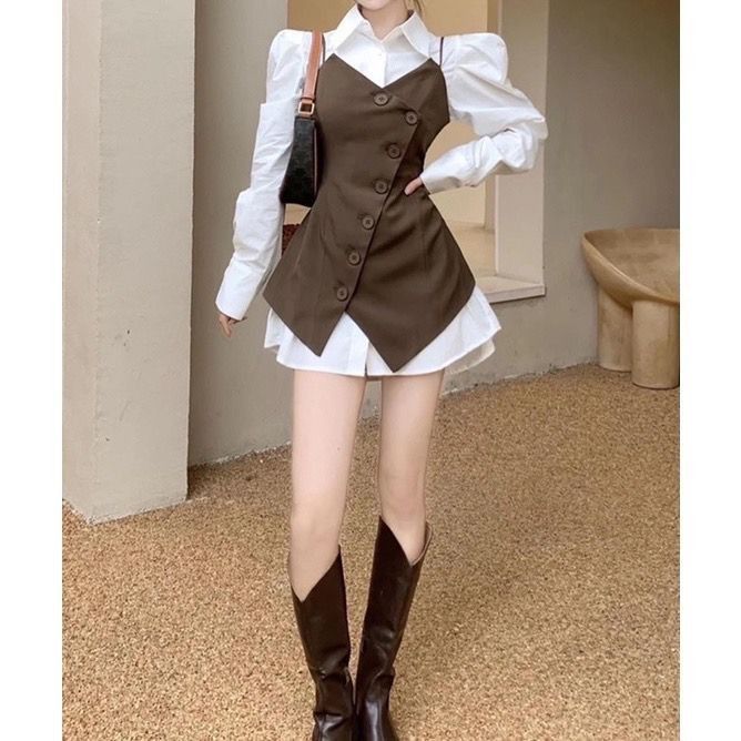 Person in a white shirt and brown vest with long boots and a shoulder bag