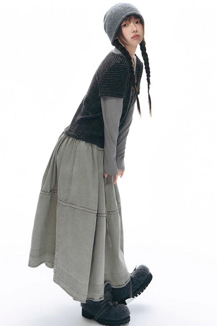 Woman in a beanie and long skirt with braids on a white background