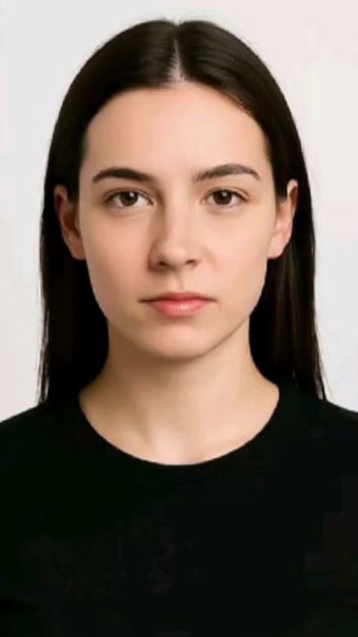 Woman with long black hair wearing a black shirt against a white background