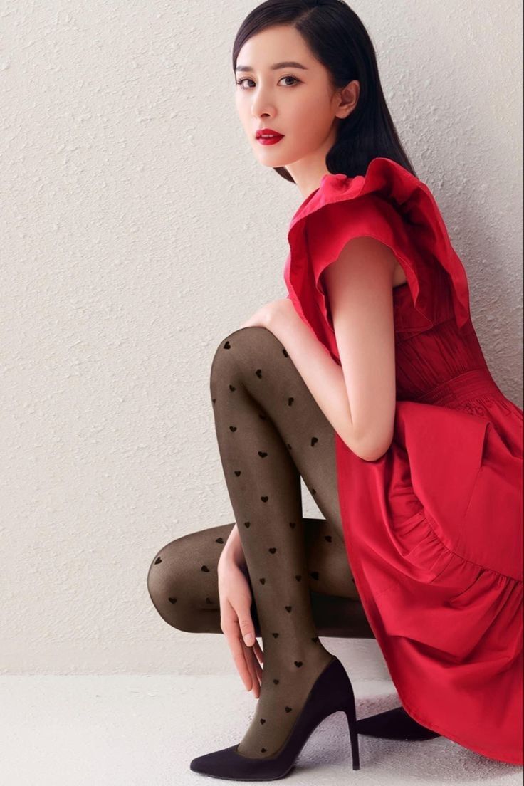 Woman in a red dress and heart-patterned tights posing indoors