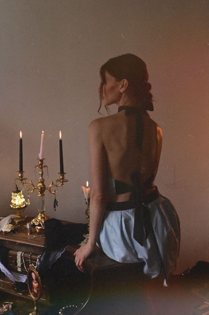 Woman with exposed back sitting on a wooden surface with candles