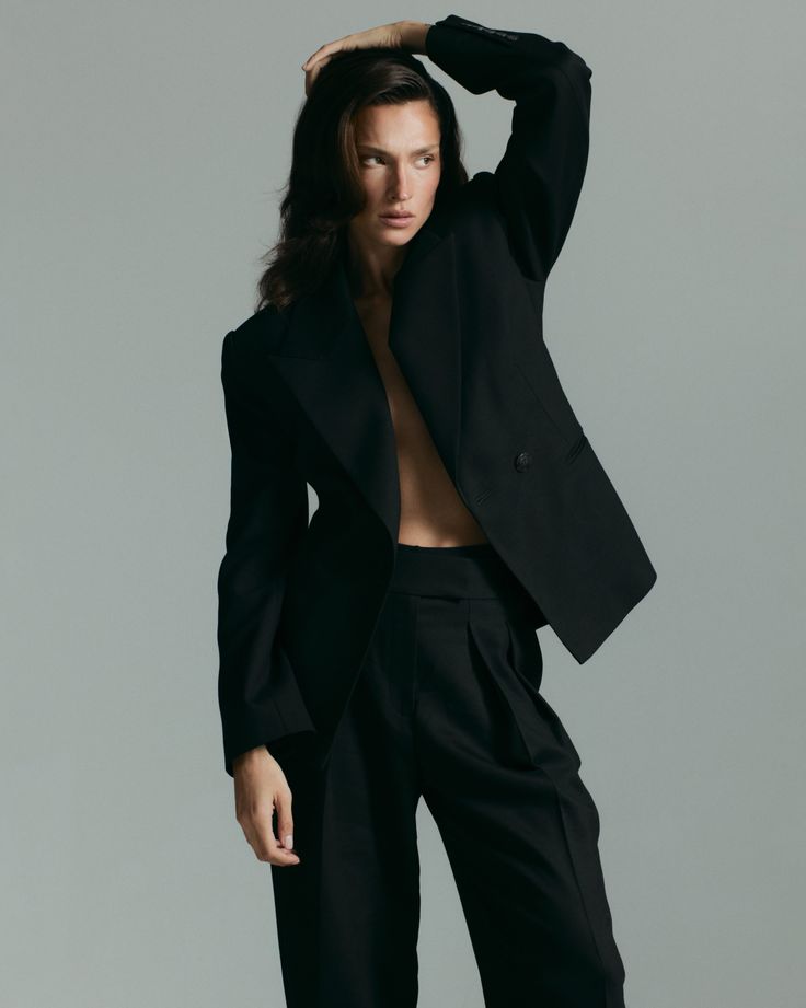Woman in an open black suit jacket with exposed skin in a studio
