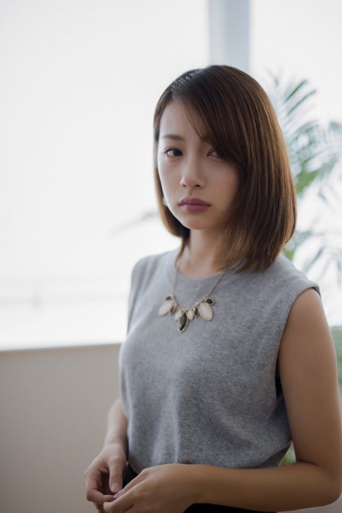 Woman with short hair and a gray top wearing a statement necklace indoors