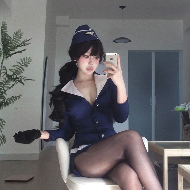 Woman in a flight attendant uniform taking a selfie indoors