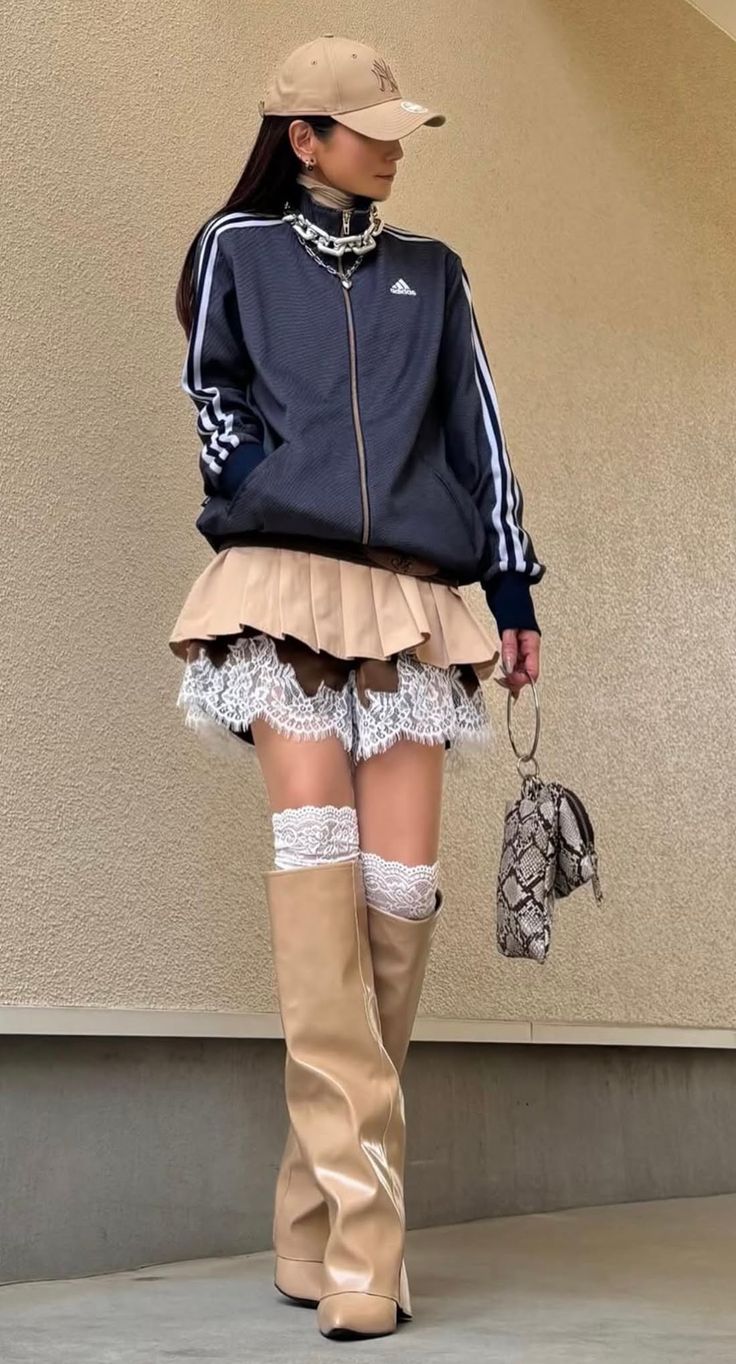 Person in a track jacket, pleated skirt with lace trim, and thigh-high boots