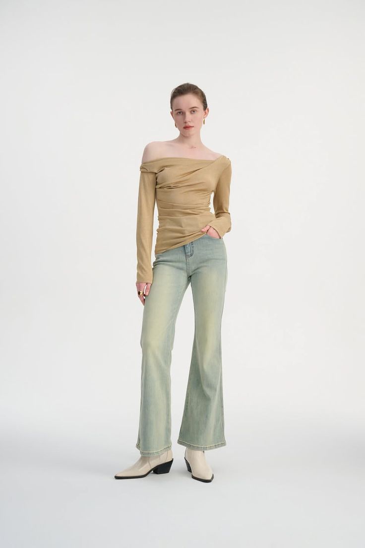 Woman in an off-shoulder top and flared jeans posing in a studio