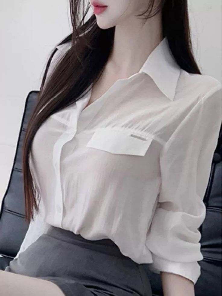 Woman with long dark hair wearing a sheer white shirt and grey skirt