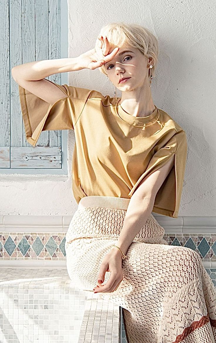Woman with short blonde hair shielding her eyes from the sun