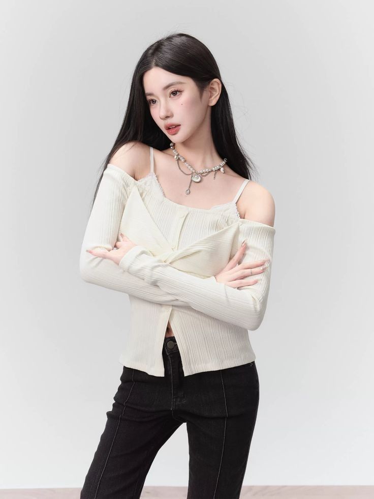 Woman with long black hair wearing an off-shoulder top and black jeans
