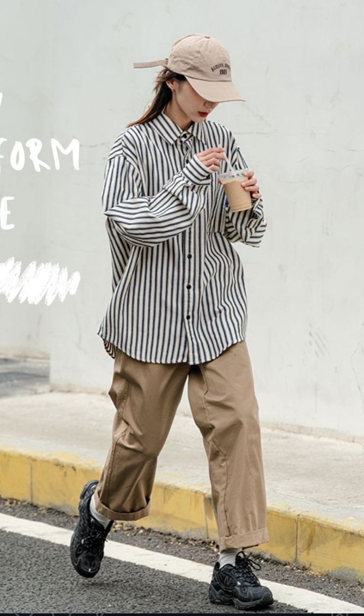 Person in a striped shirt, khaki pants, and a baseball cap walking outdoors