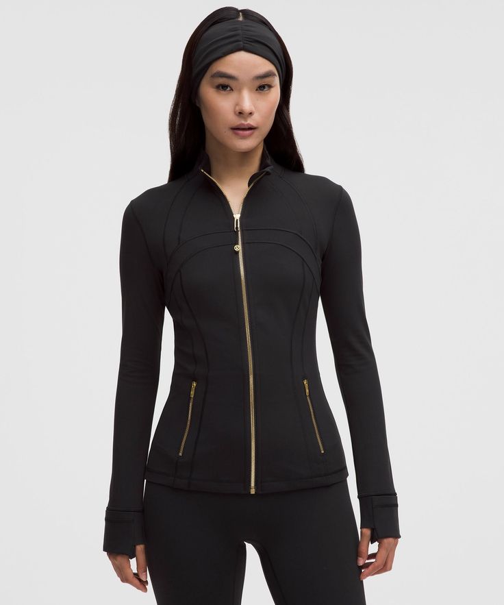 Woman in a black athletic jacket with a gold zipper and a matching headband