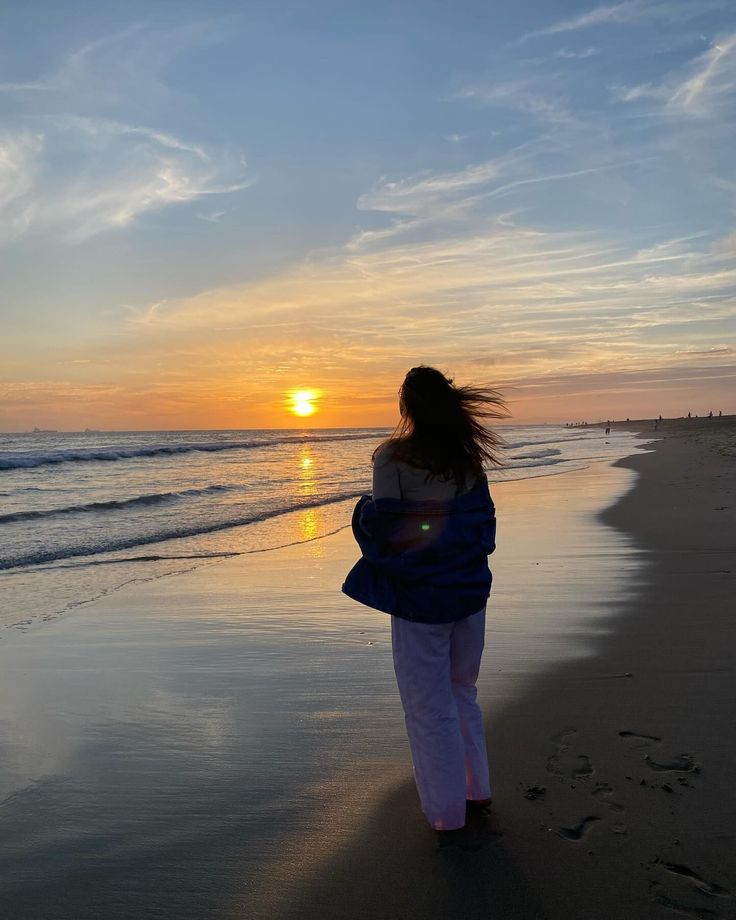 Person with long hair watching the sunset on a beach