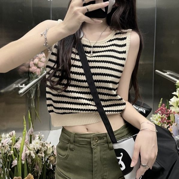 Person in a striped crop top and green pants taking a mirror selfie