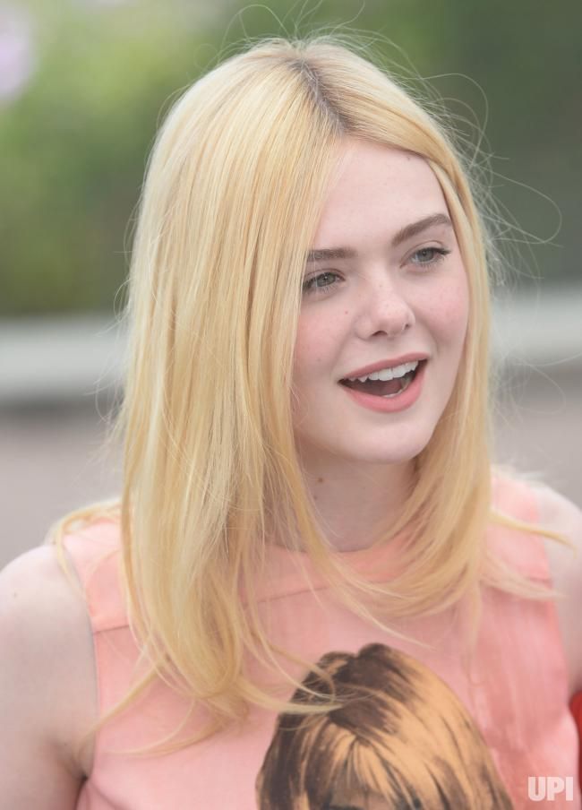 Blonde woman with long hair and freckles wearing a pink top outdoors