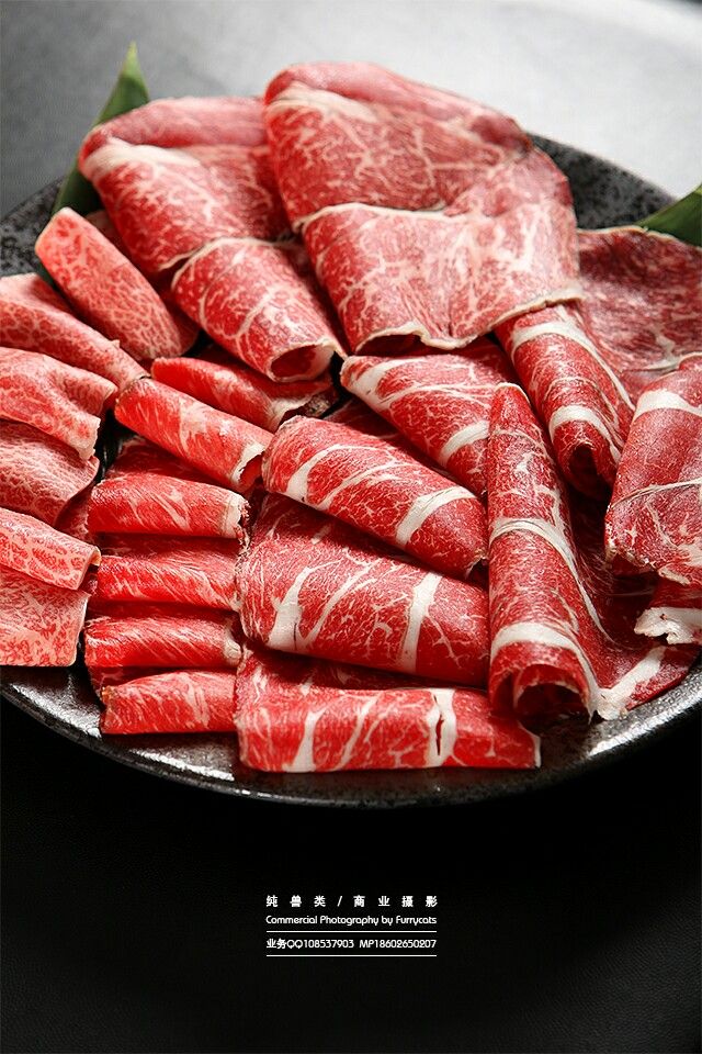 Close up of thinly sliced raw beef with marbling on a dark plate