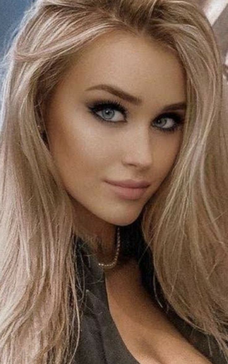 Woman with blonde hair and blue eyes wearing heavy eye makeup and a necklace