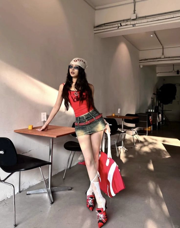 Woman in a red top and denim mini skirt posing in an indoor setting