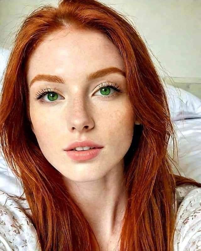 Woman with red hair and green eyes looking directly at the camera