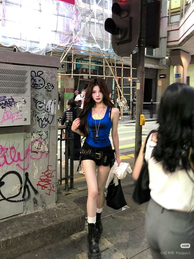 Woman in a blue tank top and black shorts walking on a city street
