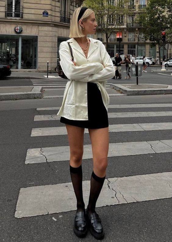 Woman with blonde hair in a white shirt and black mini skirt on a city street