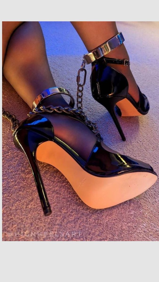 Feet in black high heels with metal ankle cuffs and chains