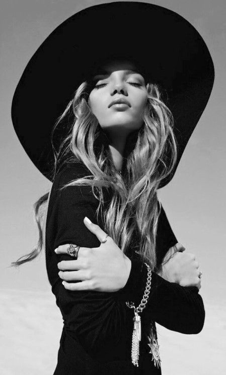 Woman in a wide brim hat with closed eyes and dramatic lighting