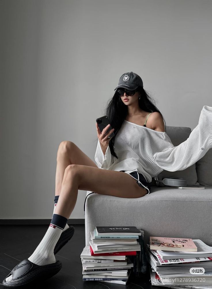 Woman in a baseball cap and off-shoulder top sitting on a couch