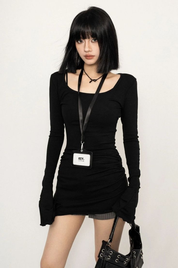 Woman with short black hair wearing a black dress and a lanyard