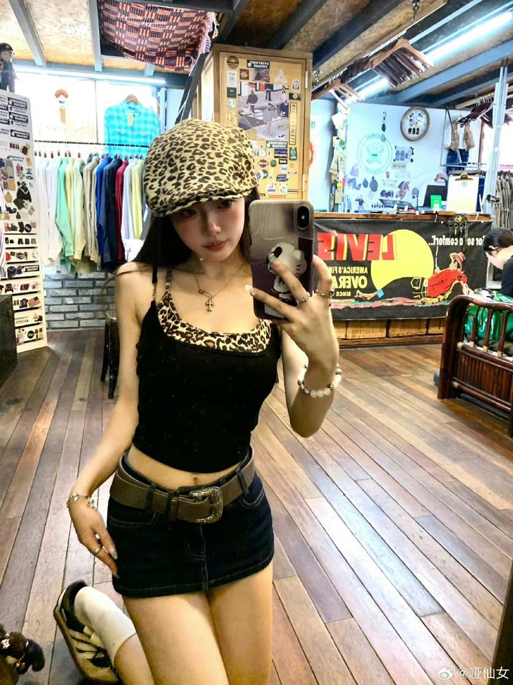 Woman in a leopard print hat and denim mini skirt taking a mirror selfie