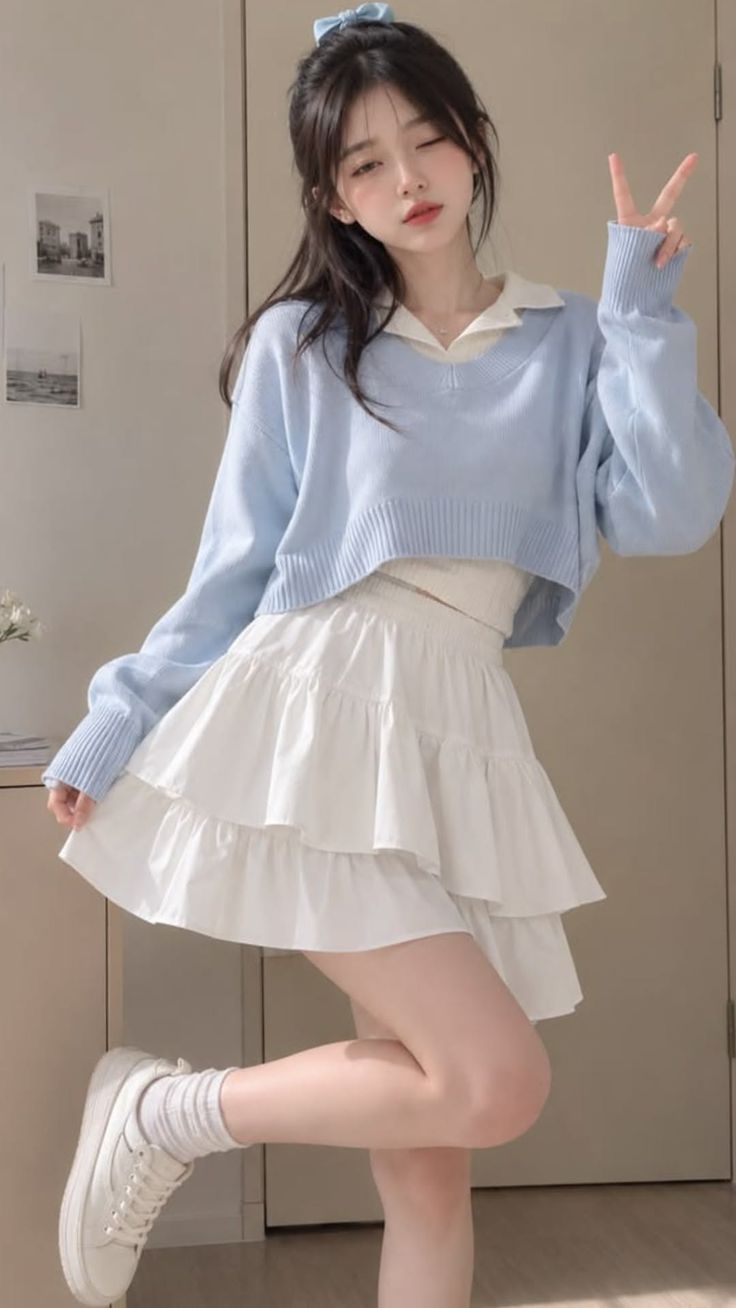 Woman in a blue sweater and white tiered skirt posing indoors