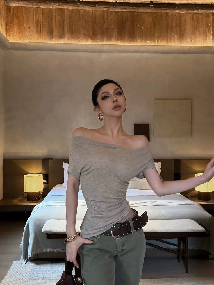 Woman in an off-shoulder top and jeans posing in a bedroom