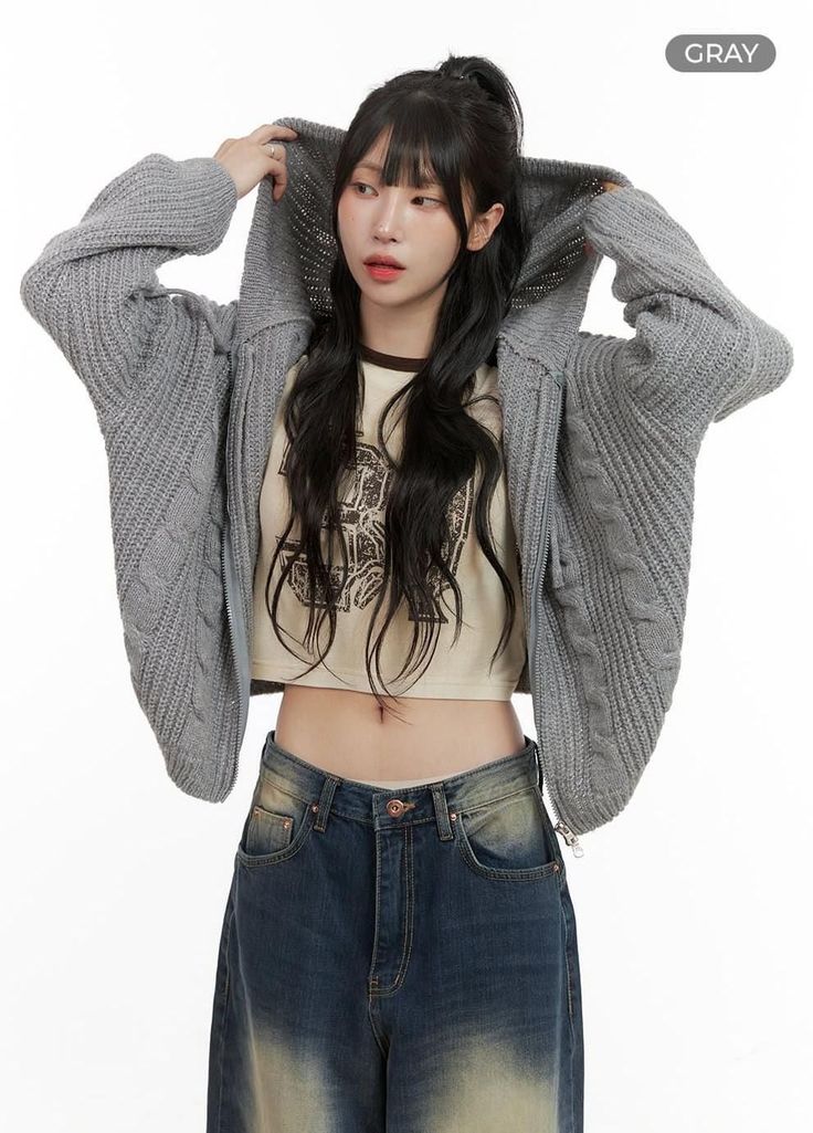Woman in a gray knitted cardigan, crop top, and wide leg jeans
