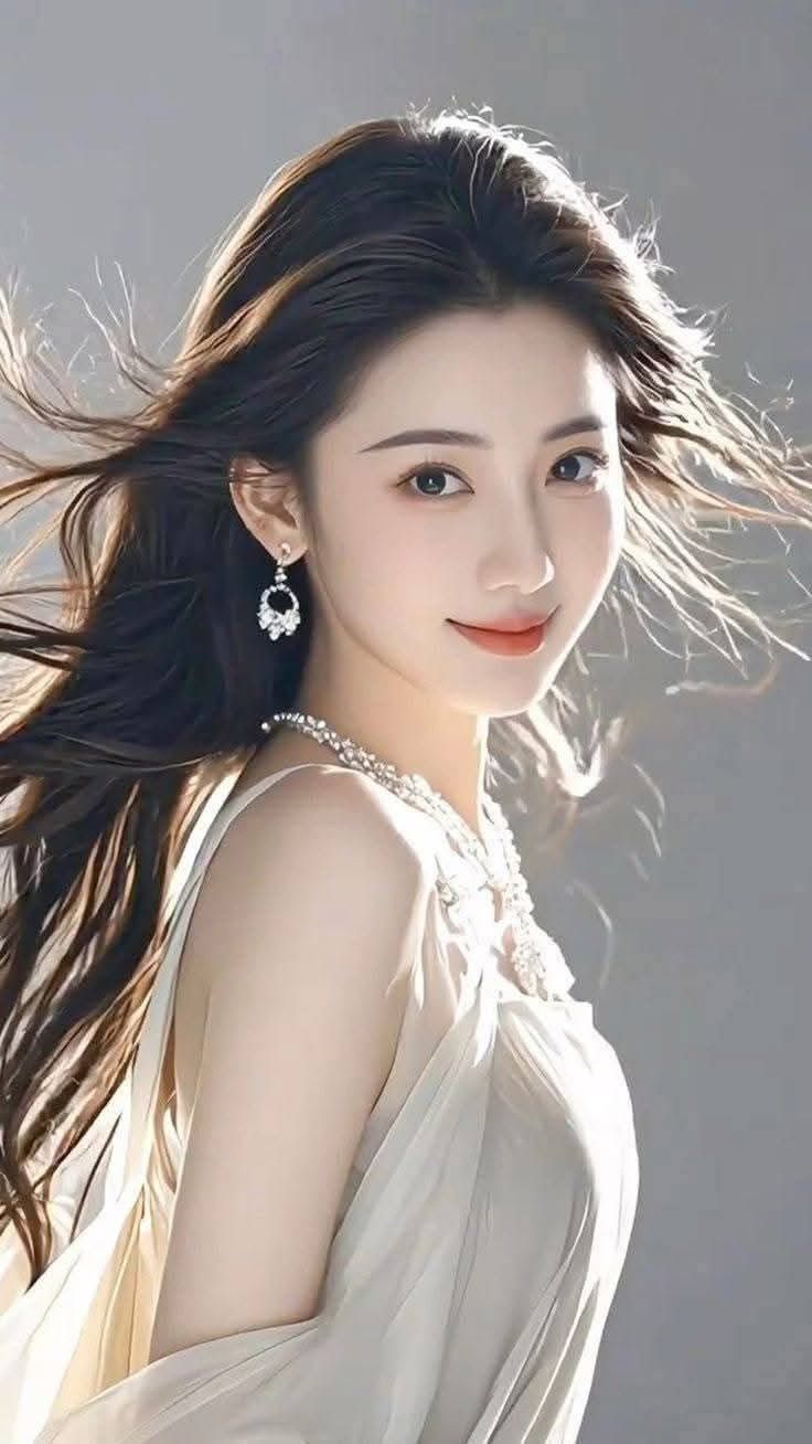 Woman with long flowing hair wearing a white dress and jewelry
