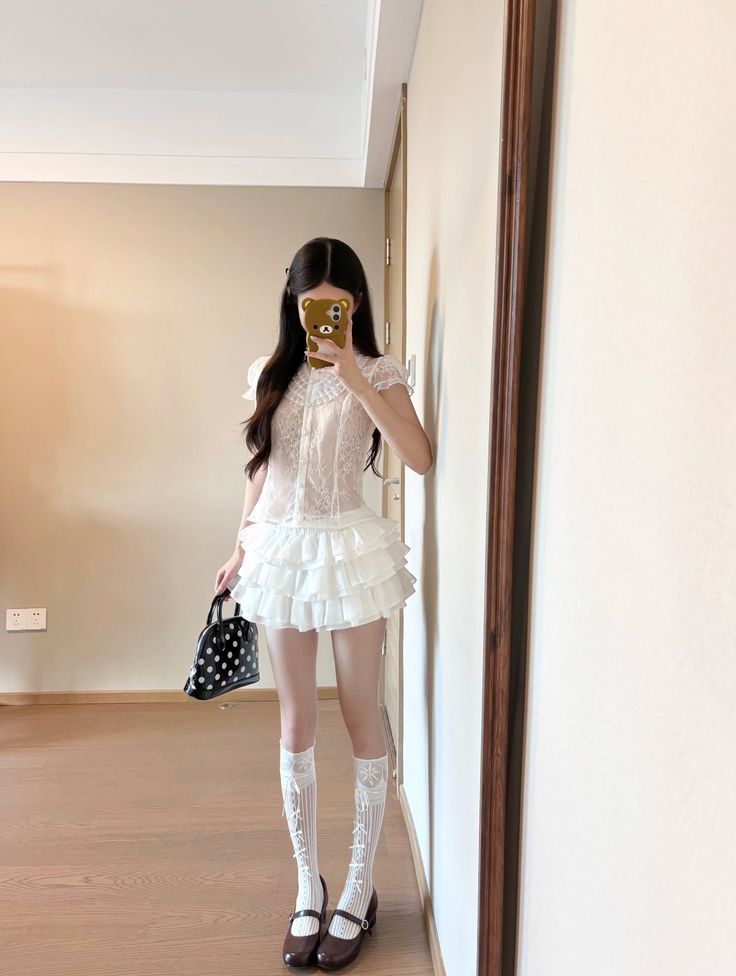 Woman in a white lace top and ruffle skirt taking a mirror selfie