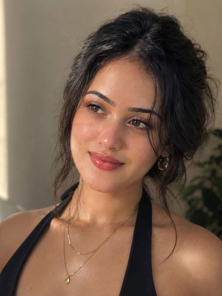 Woman with dark hair wearing a black halter top and gold jewelry