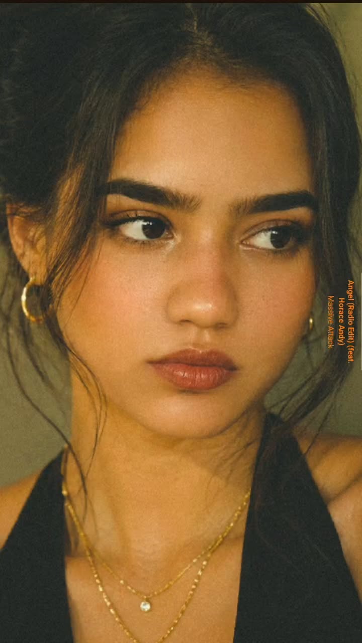 Woman with dark hair and gold jewelry looking to the side