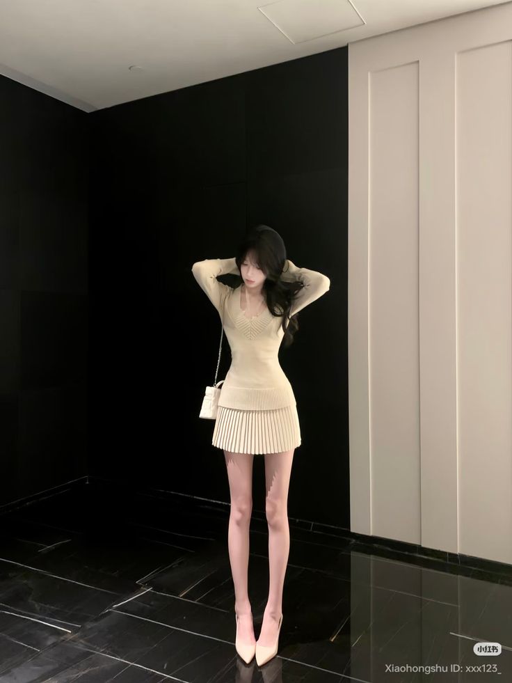 Woman in a beige mini dress and high heels posing indoors
