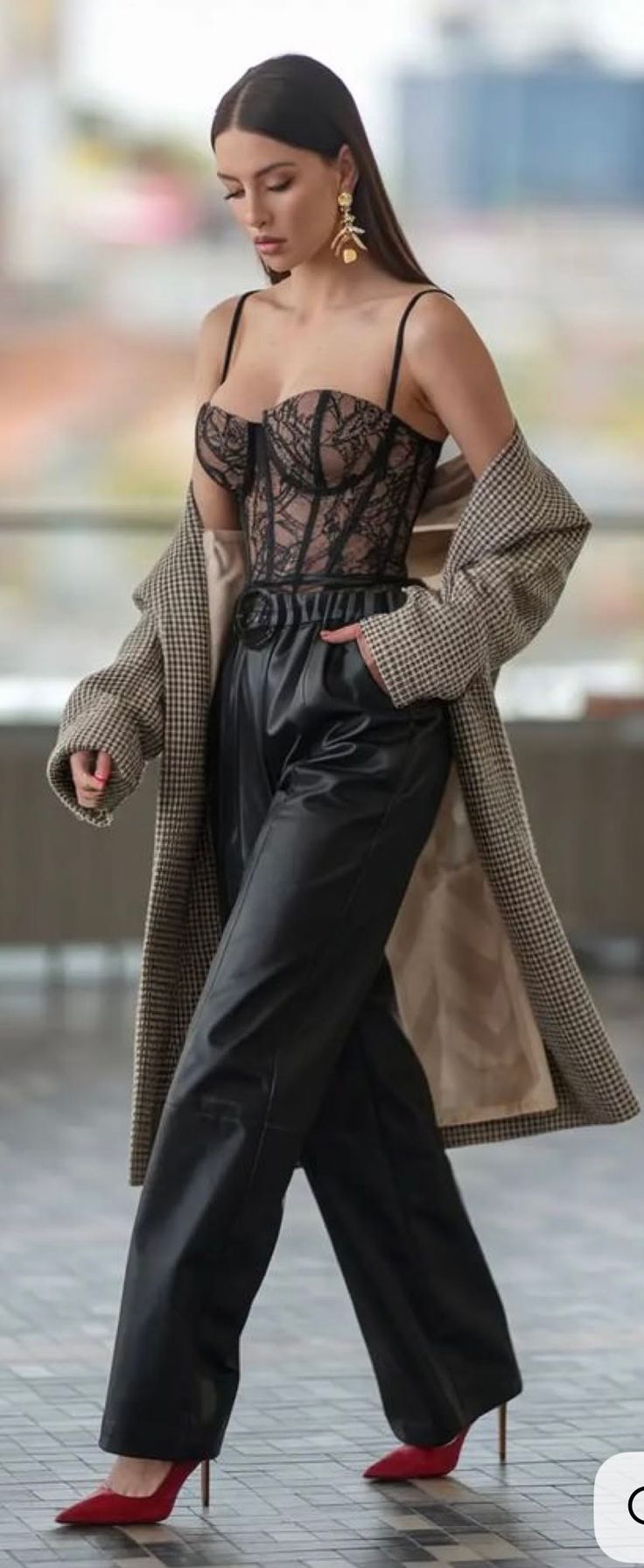 Woman in a black lace corset, leather pants, and a long coat outdoors