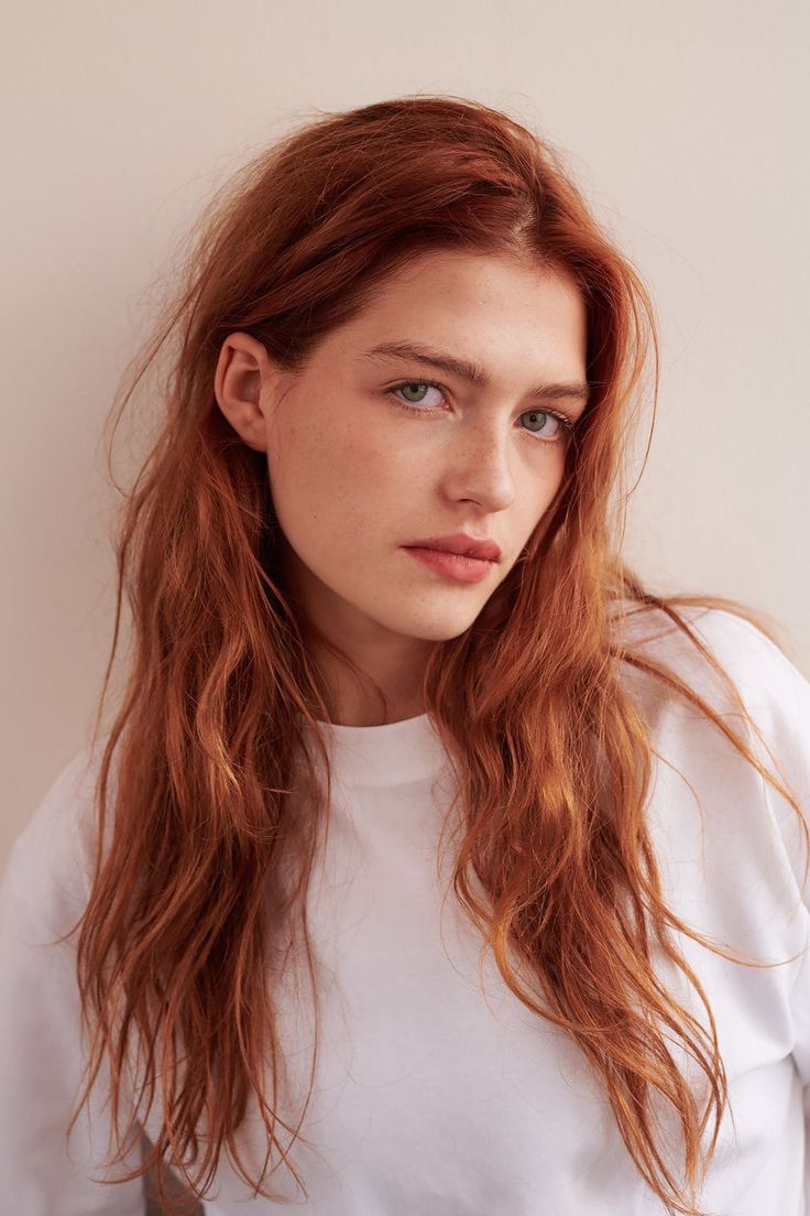 Woman with long red hair and freckles wearing a white t-shirt