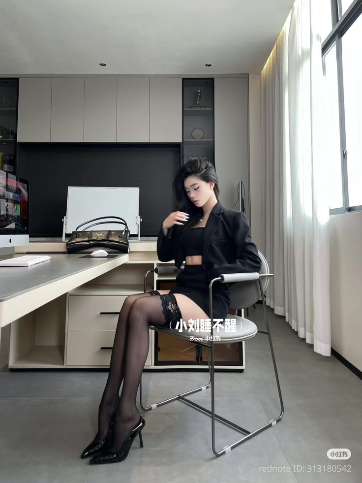 Woman in a black blazer, crop top, and mini skirt with thigh-high stockings in an office