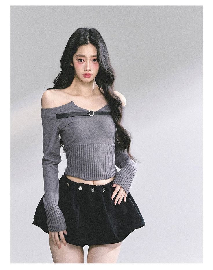 Woman with long dark hair wearing a crop top and mini skirt in a studio
